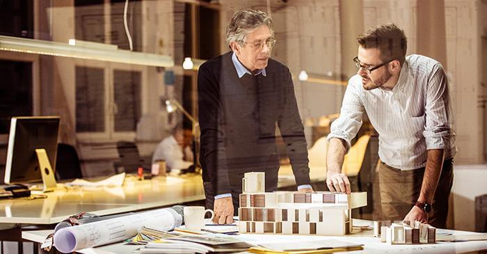 Ein Architekt und ein Bauzeichner besprechen ein Modell einer Immobilie